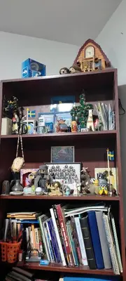a book shelf filled with books and a clock at Apartamento Marco Airport in Lima