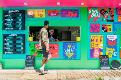 a man walking past a store with colorful signs at The Upcycled Hostel in Ica