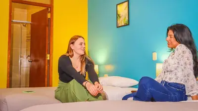 two women sitting on beds in a room at Wild Rover Cusco in Cusco