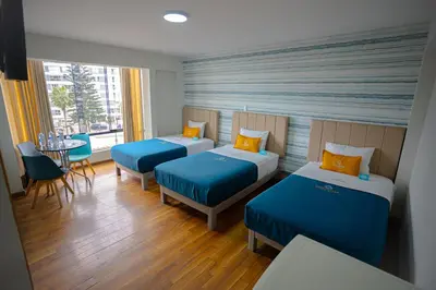 a hotel room with two beds and a table and chairs at Golden Mar Hotel in Lima