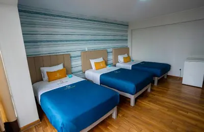 three beds in a room with blue and yellow pillows at Golden Mar Hotel in Lima