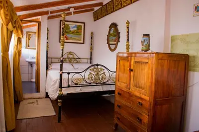 a bedroom with a bed and a wooden dresser at Hotel Museo Casona Ugarte Leon in Concepción