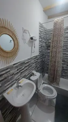 a bathroom with a sink and a toilet and a mirror at El Capricho Paracas in Paracas