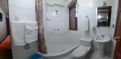 a white bathroom with a toilet and a sink at Tierra del Inka in Cusco