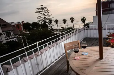 a table with two glasses of wine on a balcony at Villa Barranco by Ananay Hotels in Lima