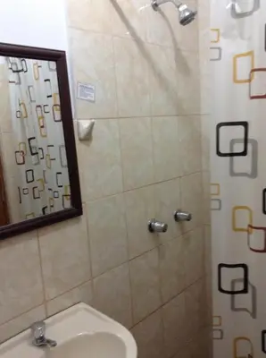 a bathroom with a shower and a toilet and a mirror at Hostal La Estancia in Ica