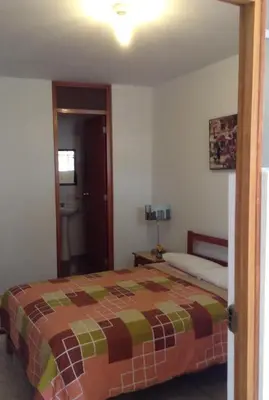 a bedroom with a bed and a door to a bathroom at Hostal La Estancia in Ica
