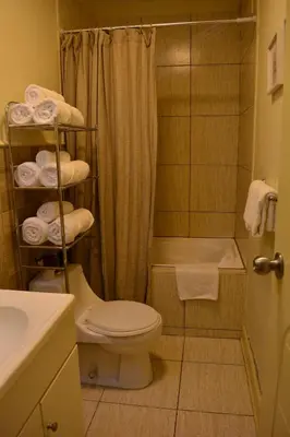 a bathroom with a toilet and a shower with towels at Kangaroo Wasi Airport Bed & Breakfast in Lima
