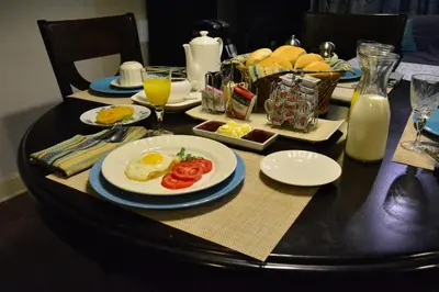 a table with a plate of eggs and tomatoes on it at Kangaroo Wasi Airport Bed & Breakfast in Lima