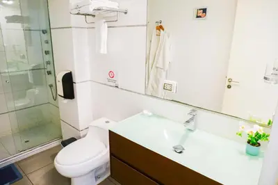 a bathroom with a toilet and a sink and a mirror at Apart Hotel Petit Palace Suites in Lima