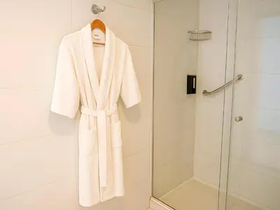 a robe is hanging in a shower in a bathroom at Apart Hotel Petit Palace Suites in Lima