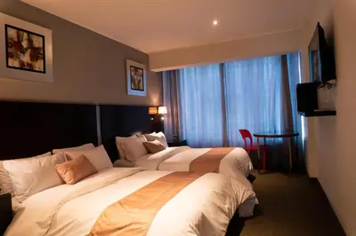a hotel room with two beds and a window at Apart Hotel Petit Palace Suites in Lima