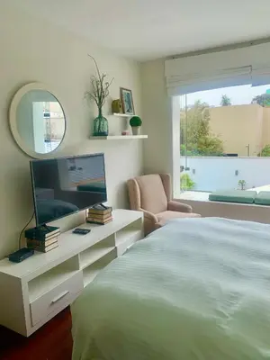 a bedroom with a bed and a tv and a chair at Lindos Apartamentos en San Isidro in Lima
