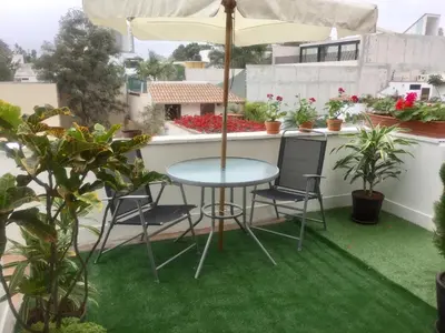 a patio with a table and chairs and an umbrella at Lindos Apartamentos en San Isidro in Lima