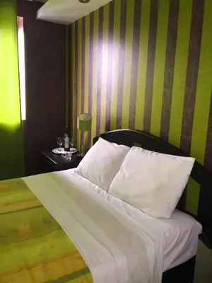 a bedroom with a bed with white sheets and green stripes at Fantasy Suites in Lima