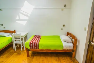 a bedroom with a bed and a table with a chair at Tucan Hostel in Cusco