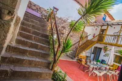 a staircase leading to a building with tables and chairs at Tucan Hostel in Cusco
