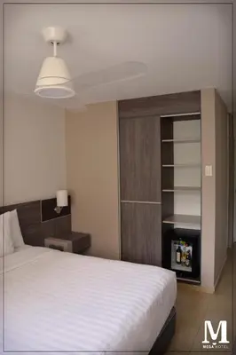 a bedroom with a white bed and a book shelf at Hotel Mega in Lima