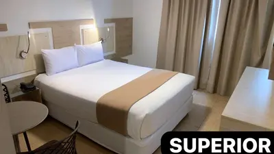a hotel room with a large bed and a table at Hotel Mega in Lima