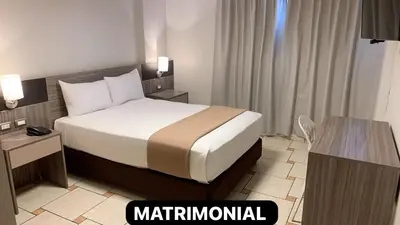 a hotel room with a bed and a desk at Hotel Mega in Lima