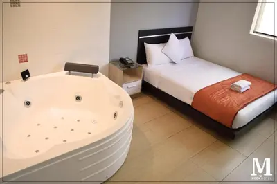a bathroom with a tub next to a bed at Hotel Mega in Lima