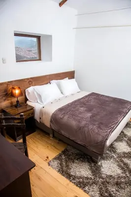 a bedroom with a bed and a table and a window at Hotel Casa Fierro Cusco in Cusco
