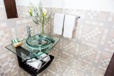 a bathroom with a glass sink with a vase at Hotel Casa Fierro Cusco in Cusco