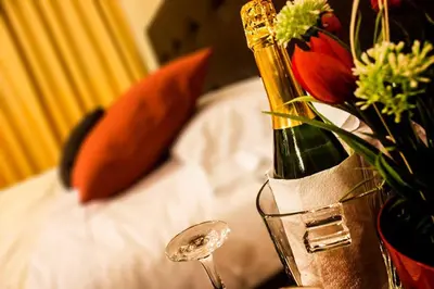 a bottle of champagne and a vase of flowers on a bed at Hotel Queen in Lima