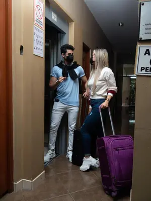 a man and a woman standing in a hallway with luggage at Hotel Queen in Lima