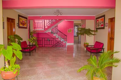 a hallway with pink walls and chairs and a staircase at Hotel Mi Casa in Ayacucho