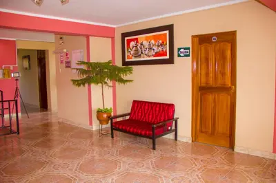 a living room with a red chair and a plant at Hotel Mi Casa in Ayacucho