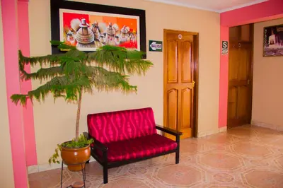 a red chair in a room with a plant at Hotel Mi Casa in Ayacucho