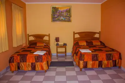 a hotel room with two beds and a table at Hotel Mi Casa in Ayacucho