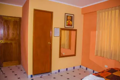 a bedroom with orange walls and a door and a mirror at Hotel Mi Casa in Ayacucho