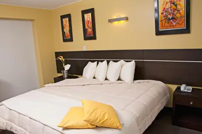 a bedroom with a large white bed with yellow pillows at Flamante Hotel & Suite in Lima