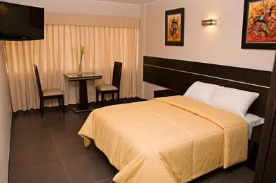 a hotel room with a bed and a table with chairs at Flamante Hotel & Suite in Lima