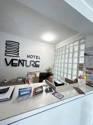 a woman sitting at a hotel service desk at Hotel Venture in Chincha Alta