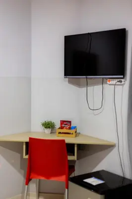 a desk with a red chair and a television on a wall at Hotel Venture in Chincha Alta