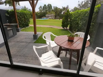 a patio with a wooden table and white chairs at Villas de Cieneguilla in Cieneguilla