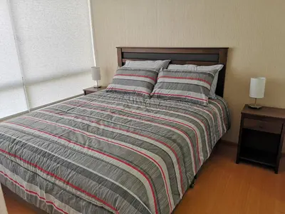 a bed with a striped comforter in a bedroom at Lima Flats 3 in Lima