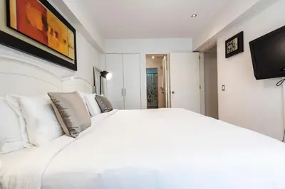 a white bedroom with a white bed and a flat screen tv at InkaHuset Miraflores Deluxe in Lima