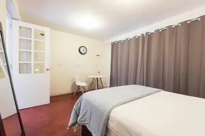 a bedroom with a bed and a table with a clock at InkaHuset Airport in Lima