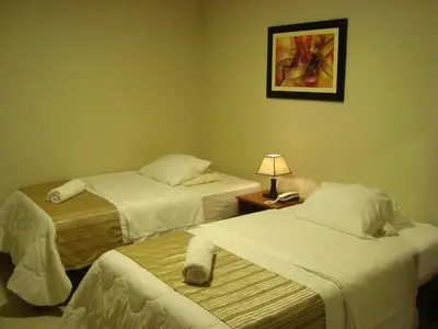 a hotel room with two beds and a lamp at PiscoMar Peru in Pisco