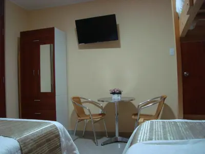 a room with a table with two chairs and a tv on the wall at PiscoMar Peru in Pisco