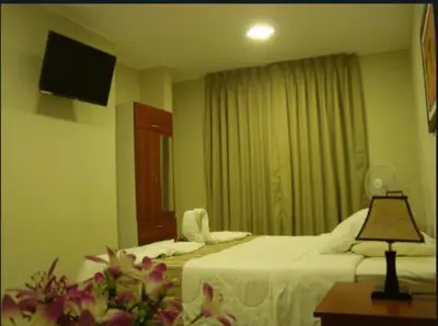 a hotel room with two beds and a television at PiscoMar Peru in Pisco