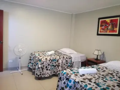 a hotel room with two beds and a fan at PiscoMar Peru in Pisco