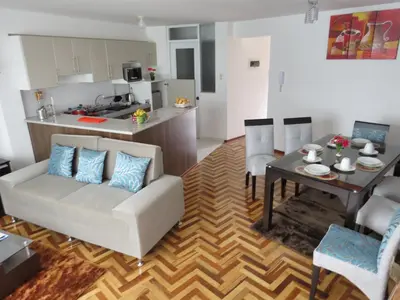 a living room with a white couch and a table at Apartamentos Quewe in Cusco