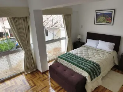 a bedroom with a bed and a large window at Apartamentos Quewe in Cusco
