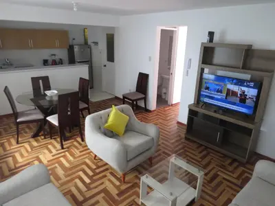 a living room with a television and a table and chairs at Apartamentos Quewe in Cusco