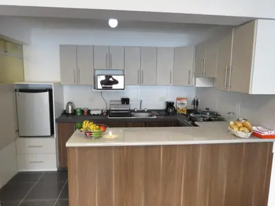 a kitchen with white cabinets and a sink and a refrigerator at Apartamentos Quewe in Cusco
